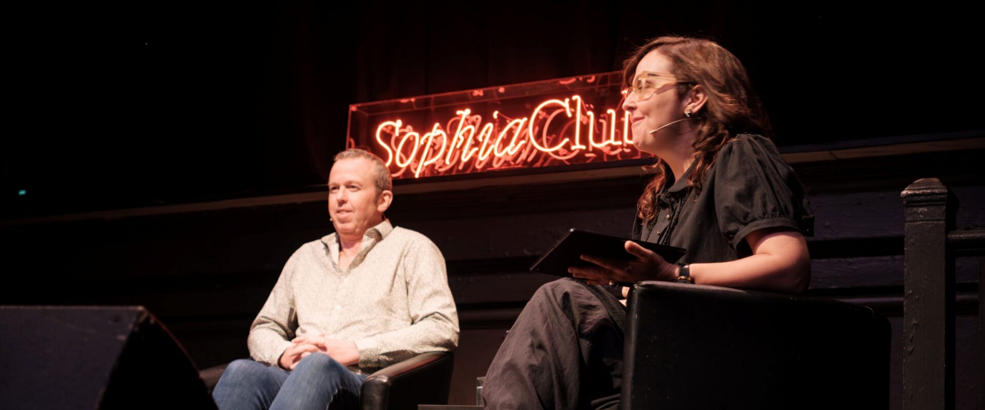 Photograph of Tony Padilla along with a Sophia Club representative in discussion sitting on stage